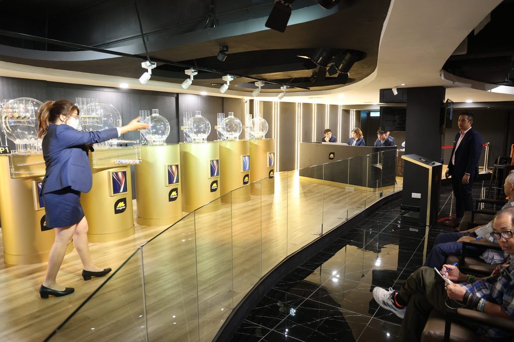 Magnum’s 4D draw process with transparent lottery drums, numbered balls and adult participants.